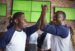 Male Friends Watching Game In Sports Bar Celebrating